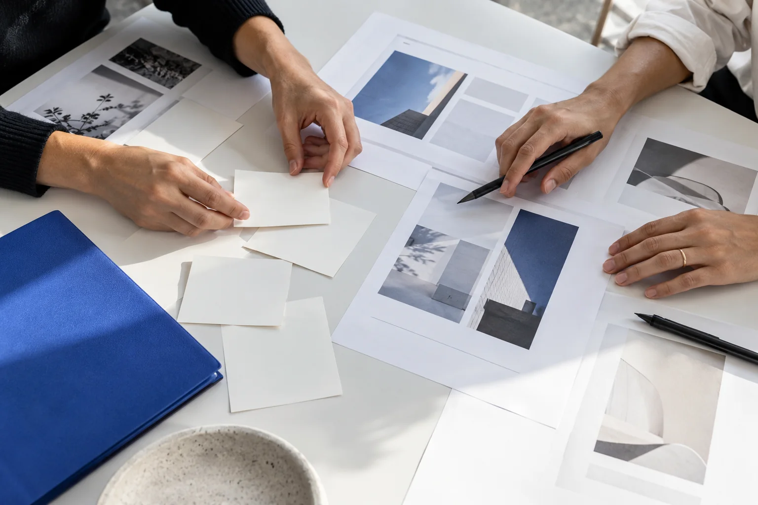 Hands arranging project cards and visual references on a white planning desk