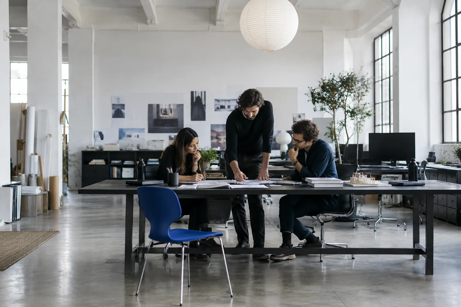 A creative team collaborating around a long table in a sunlit digital studio