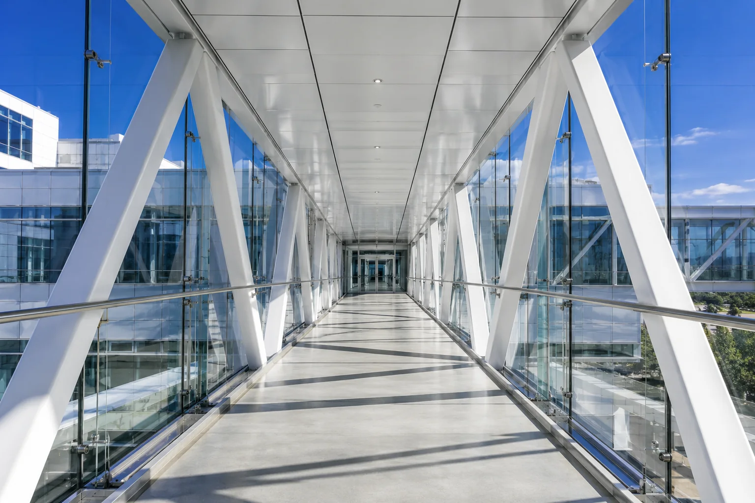 A light-filled glass bridge connecting two buildings with a clear central path