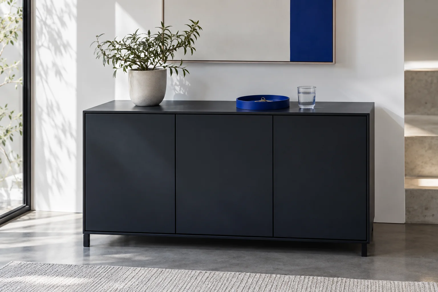 A closed matte storage cabinet in a bright office with subtle cobalt details